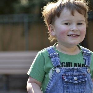 An image showing a young child smiling in a park.