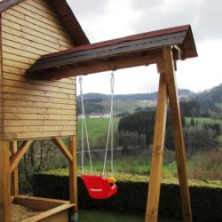 An image of a wooden playset with a treeline in the background.