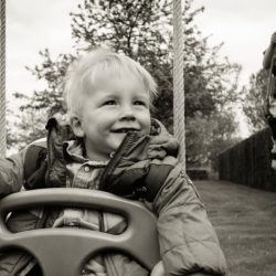 An image of two children swinging on swings in a backyard.