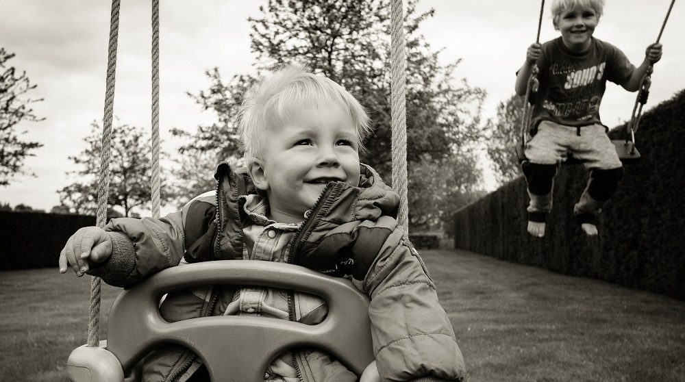 An image of two children swinging on swings in a backyard.