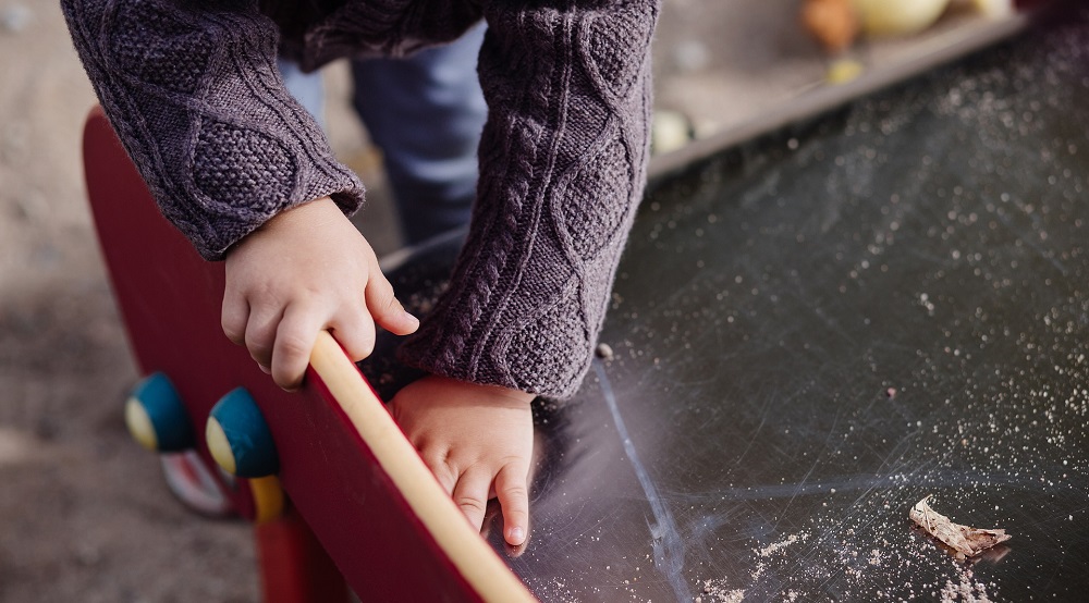 An image showing a child playing at the end of a steel bottomed slide.