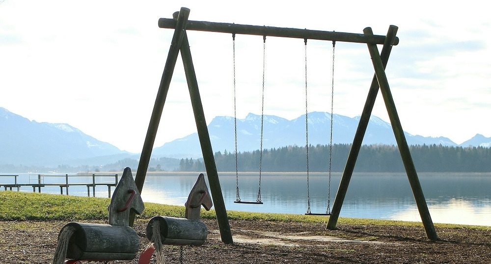 An image of a playset with two swing seats on a beach.