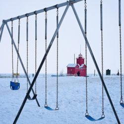 An image showing a toddler swing seat and several belt swing seats all attached to a playset in a snowfallen background.