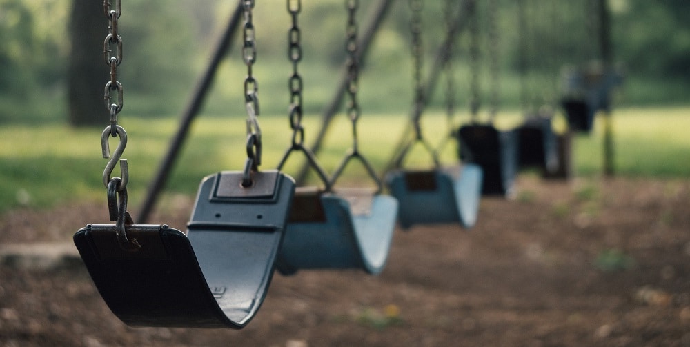 An image of a playset with two swing seats on a beach.