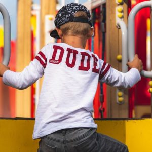 An image of a child climbing a playset with a shirt that reads, "DUDE".