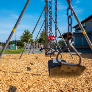 An image that shows a swing set with a child playing on it in a school.