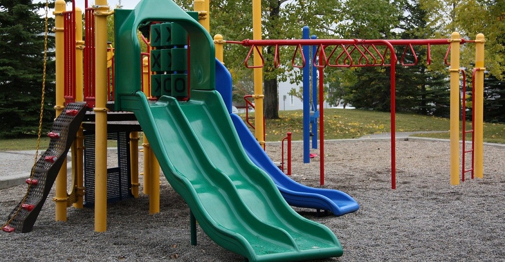 An image showing a playset with slides and monkey bars in a park.