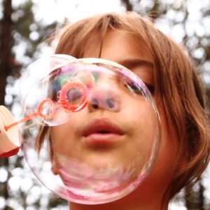 An image that shows a child blowing bubbles.