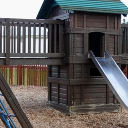 An image that shows a wooden playset with a steel slide attached to it.
