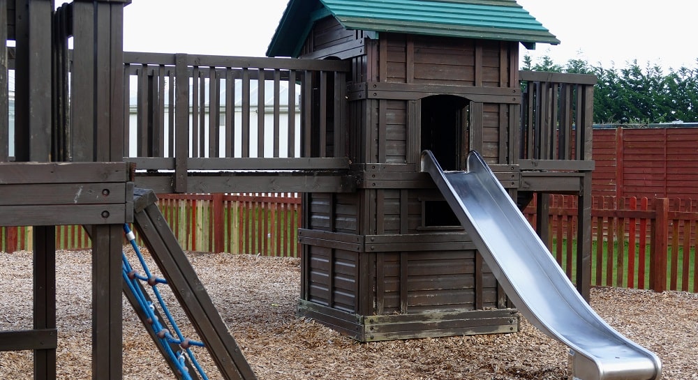 An image that shows a wooden playset with a steel slide attached to it.