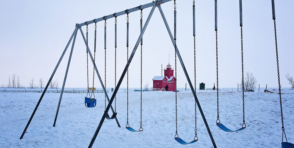 An image showing a toddler swing seat and several belt swing seats all attached to a playset in a snowfallen background.